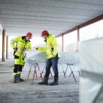 Karriere: To personer står over plantegninger på byggeplass.